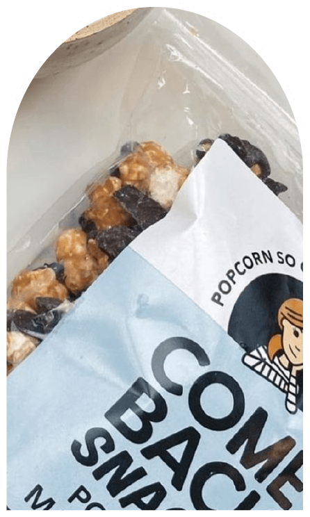 Close up cut off picture of popcorn in a plastic bag with the label Comeback Snacks 